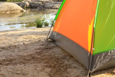 Photo of Modern camping tent on riverbank. Space for text