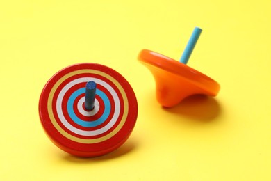 Photo of Two colorful spinning tops on yellow background, closeup