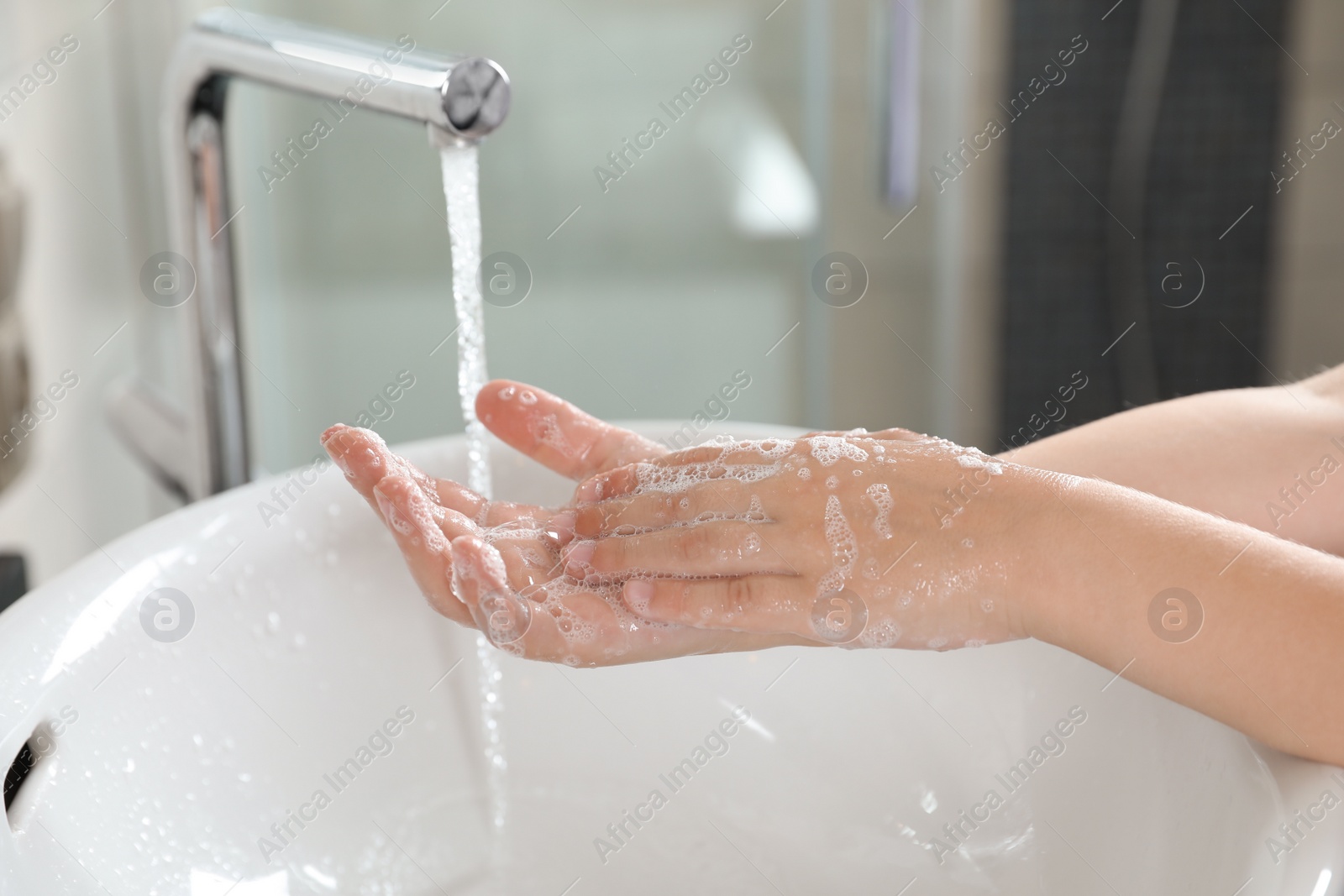 Photo of Little boy washing hands with soap over sink in bathroom, closeup