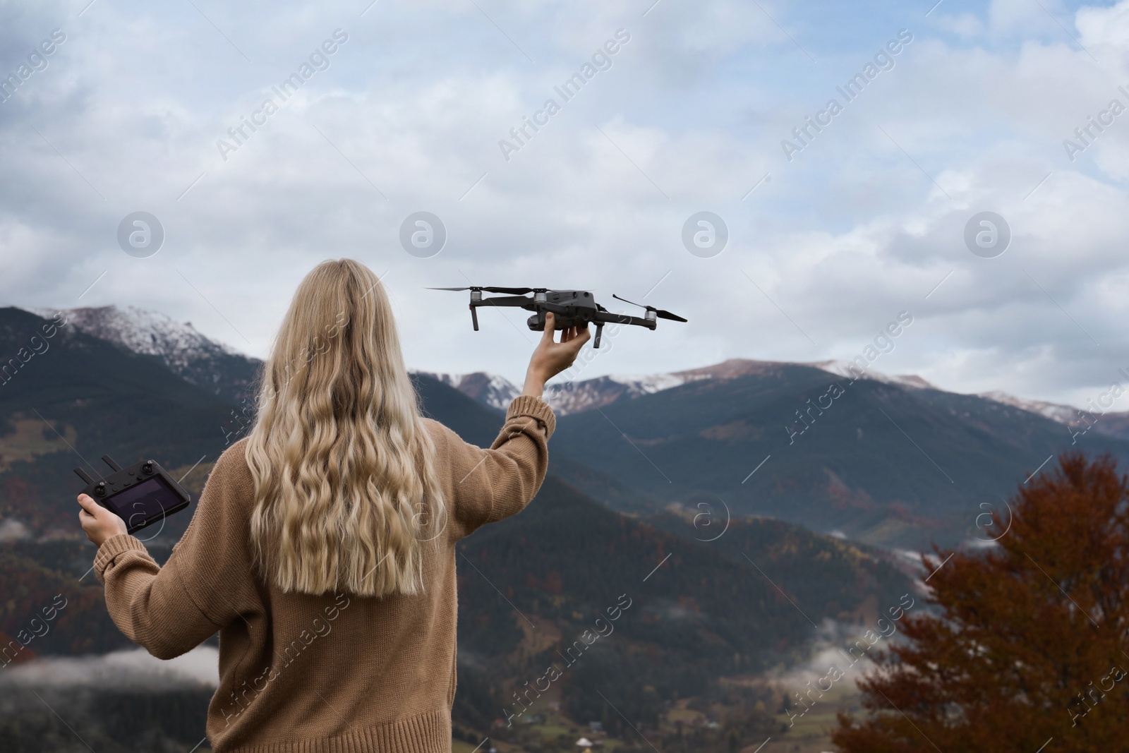 Photo of Young woman with modern drone in mountains, back view. Space for text