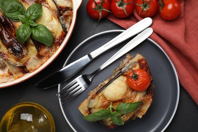 Photo of Plate of delicious eggplant lasagna served on black table, flat lay