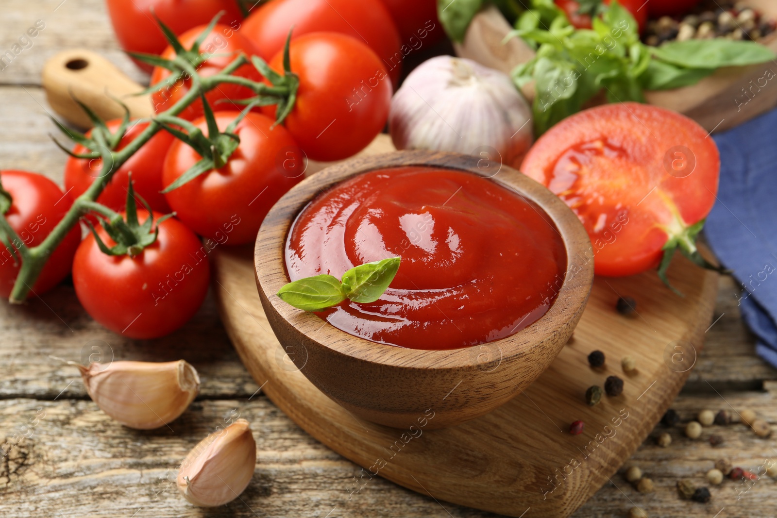 Photo of Tasty ketchup, fresh tomatoes, basil and spices on wooden table