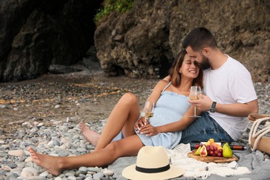 Photo of Happy young couple having picnic on beach. Space for text