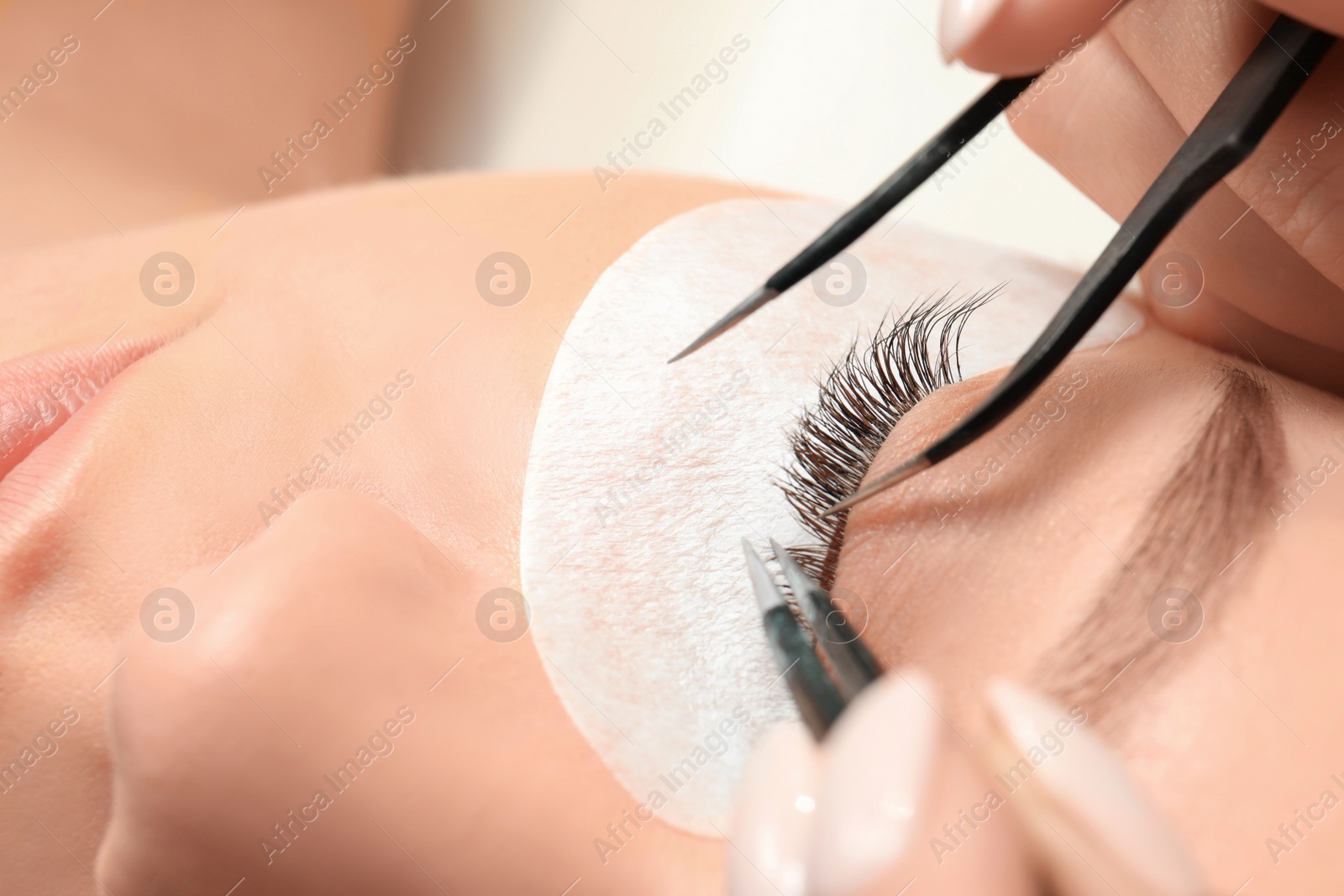 Photo of Young woman undergoing eyelash extension procedure, closeup