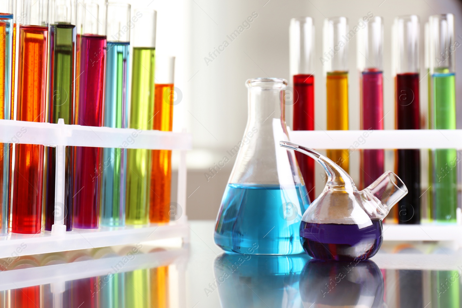 Photo of Laboratory glassware with color liquids on table. Solution chemistry