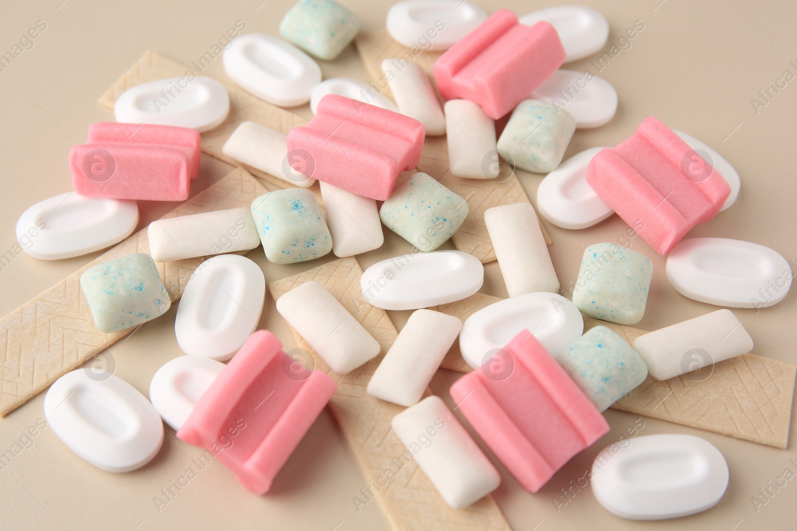 Photo of Many different chewing gums on beige background, closeup