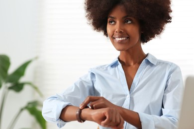 Photo of Smiling African American woman with wristwatch indoors. Space for text