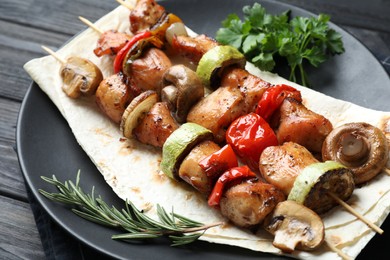 Delicious shish kebabs with vegetables and spices on table, closeup