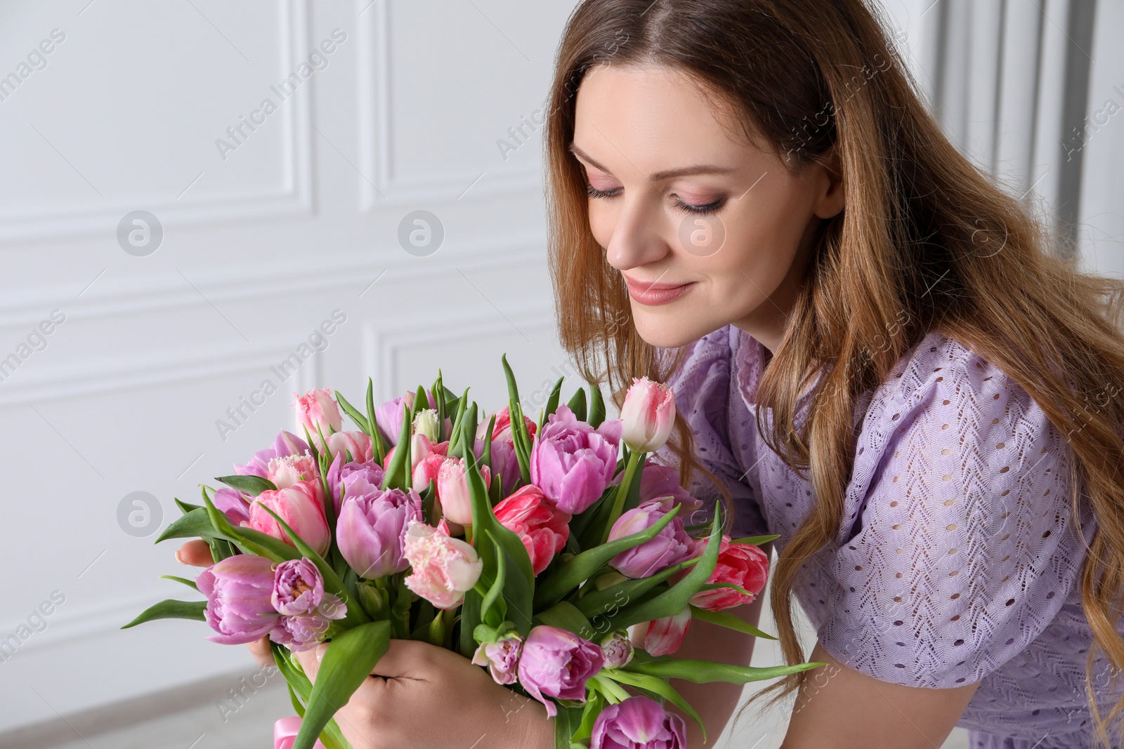 Photo of Young woman with bouquet of beautiful tulips indoors