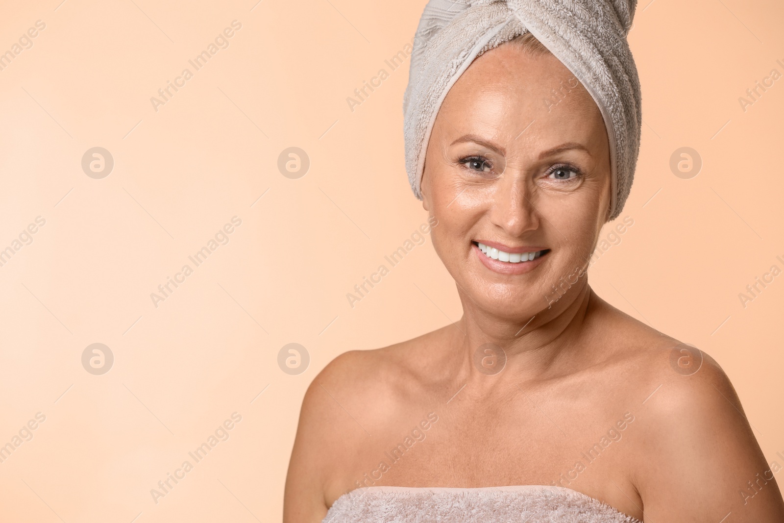 Photo of Portrait of beautiful mature woman with perfect skin on beige background. Space for text