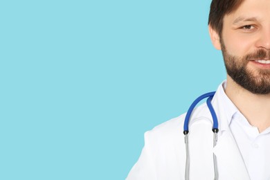 Doctor or medical assistant (male nurse) in uniform with stethoscope on turquoise background, closeup. Space for text