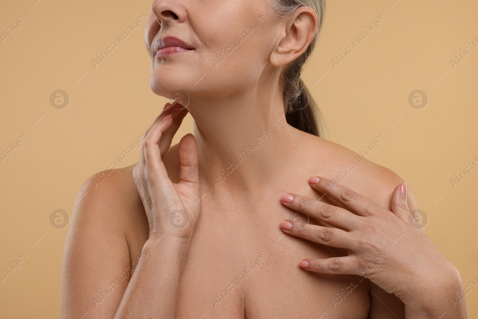 Photo of Mature woman touching her neck on beige background, closeup