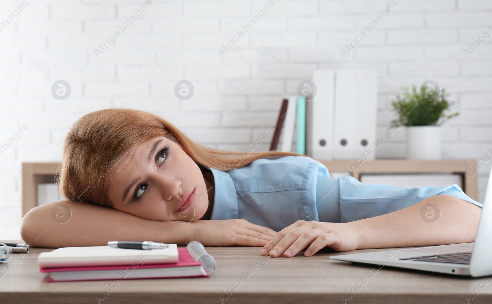 Photo of Lazy employee wasting time at table in office