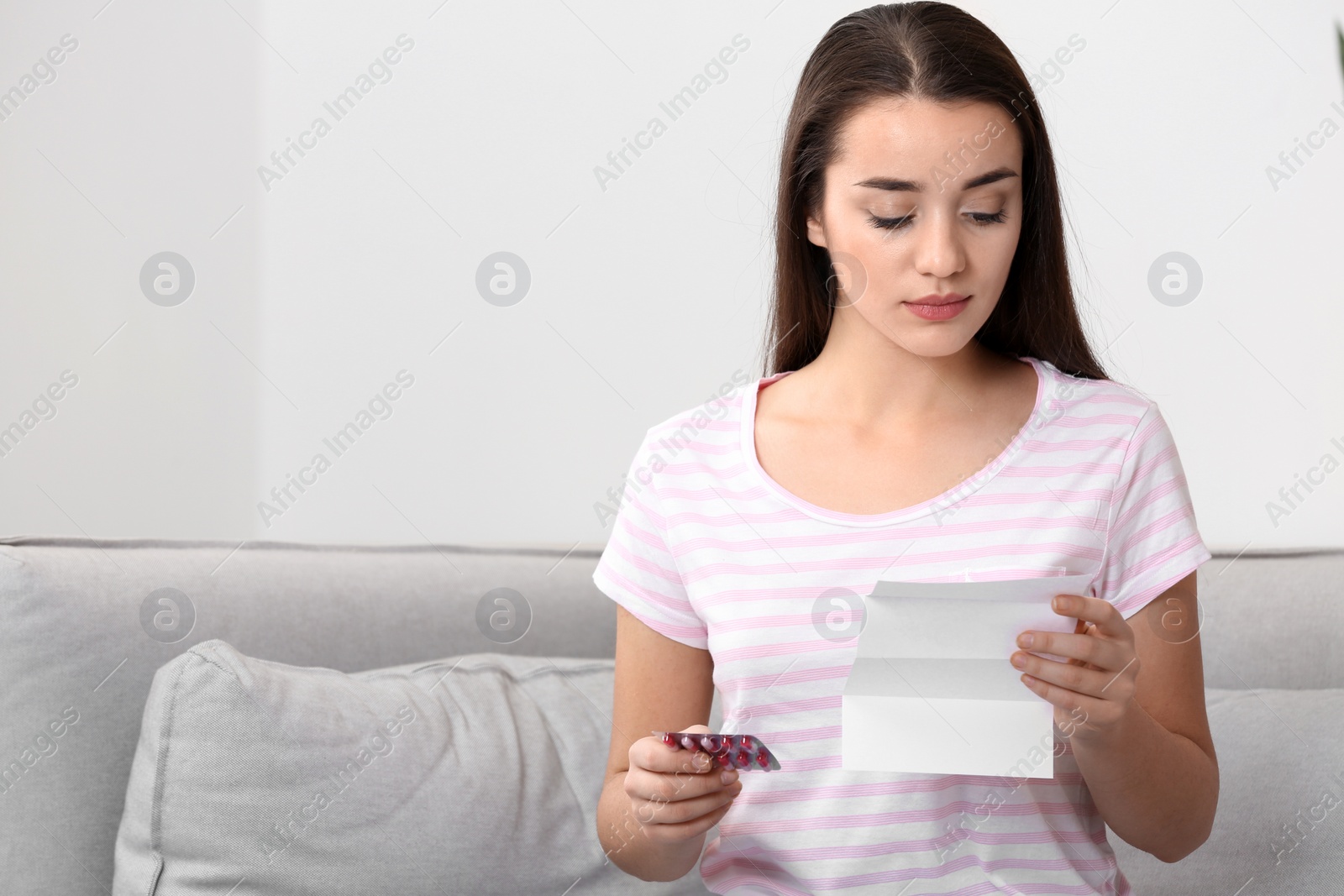 Photo of Beautiful young woman with pills at home