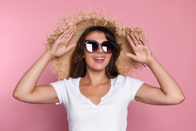 Photo of Happy beautiful woman with stylish straw hat and sunglasses on pink background