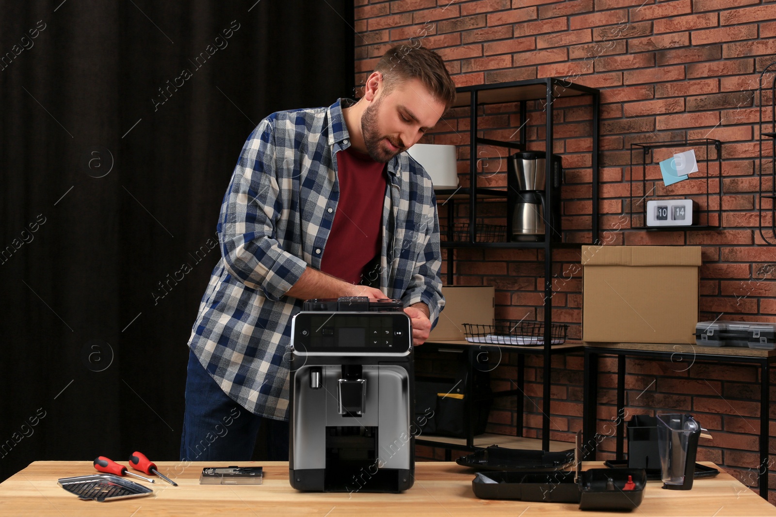 Photo of Man fixing coffee machine at table indoors