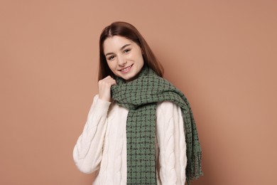 Beautiful woman in warm scarf on brown background