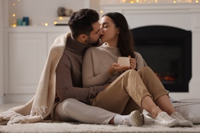 Photo of Young man kissing his girlfriend on soft carpet at home