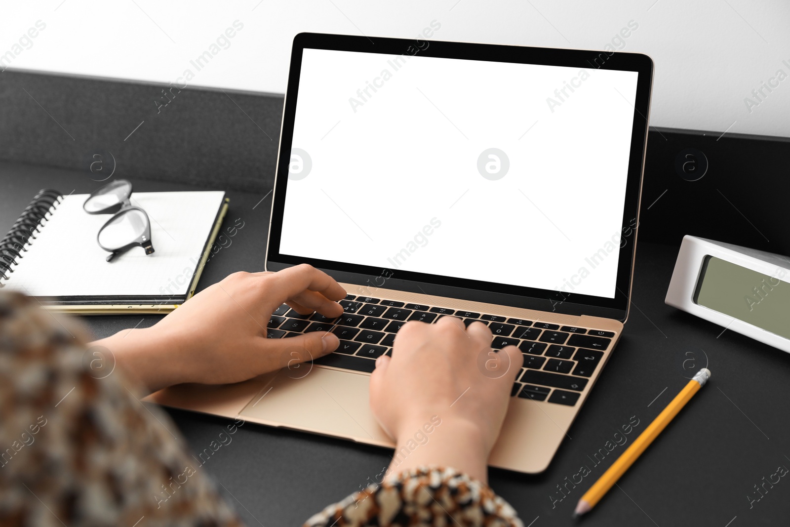 Photo of Woman working on modern laptop at black table, closeup. Space for design