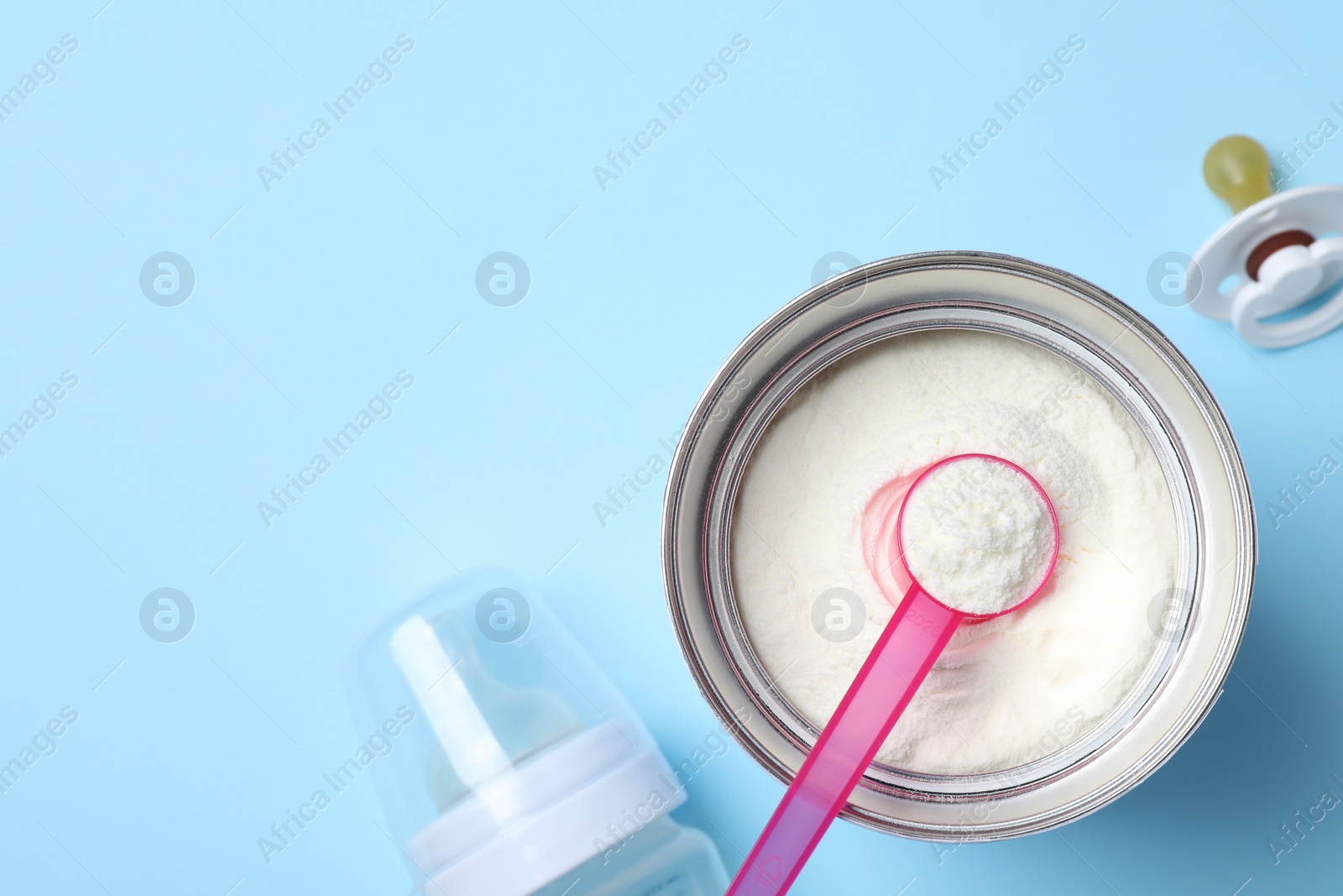 Photo of Flat lay composition with powdered infant formula on light blue background, space for text. Baby milk