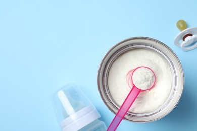 Photo of Flat lay composition with powdered infant formula on light blue background, space for text. Baby milk