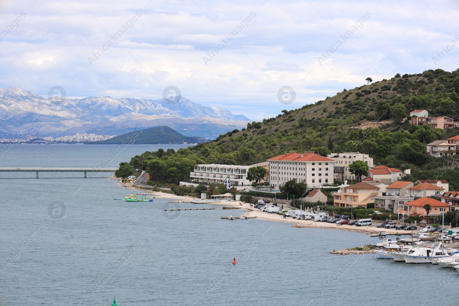 Photo of Picturesque view of town with buildings, moored boats and sea on cloudy day