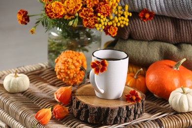 Photo of Beautiful autumn composition with cup of drink and pumpkins on wicker table
