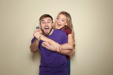 Photo of Happy young couple with car key on color background