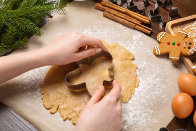 Photo of Woman making Christmas cookies with cutters at table, closeup