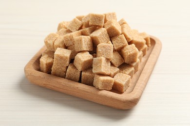 Photo of Brown sugar cubes on white wooden table