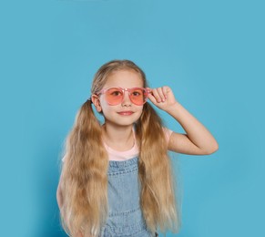 Photo of Girl in pink sunglasses on light blue background