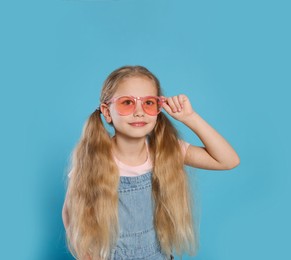 Girl in pink sunglasses on light blue background