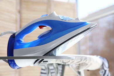 Modern electric iron on board indoors. Household appliance