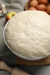 Photo of Fresh dough, rolling pin and ingredients on grey table, closeup. Cooking yeast cake
