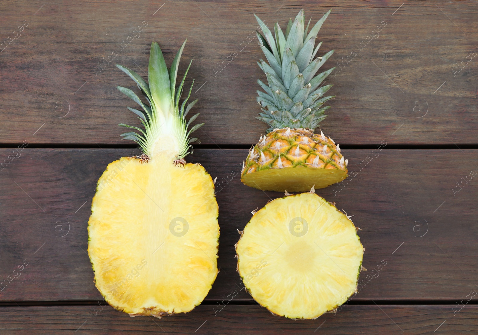 Photo of Cut ripe pineapples on wooden table, flat lay