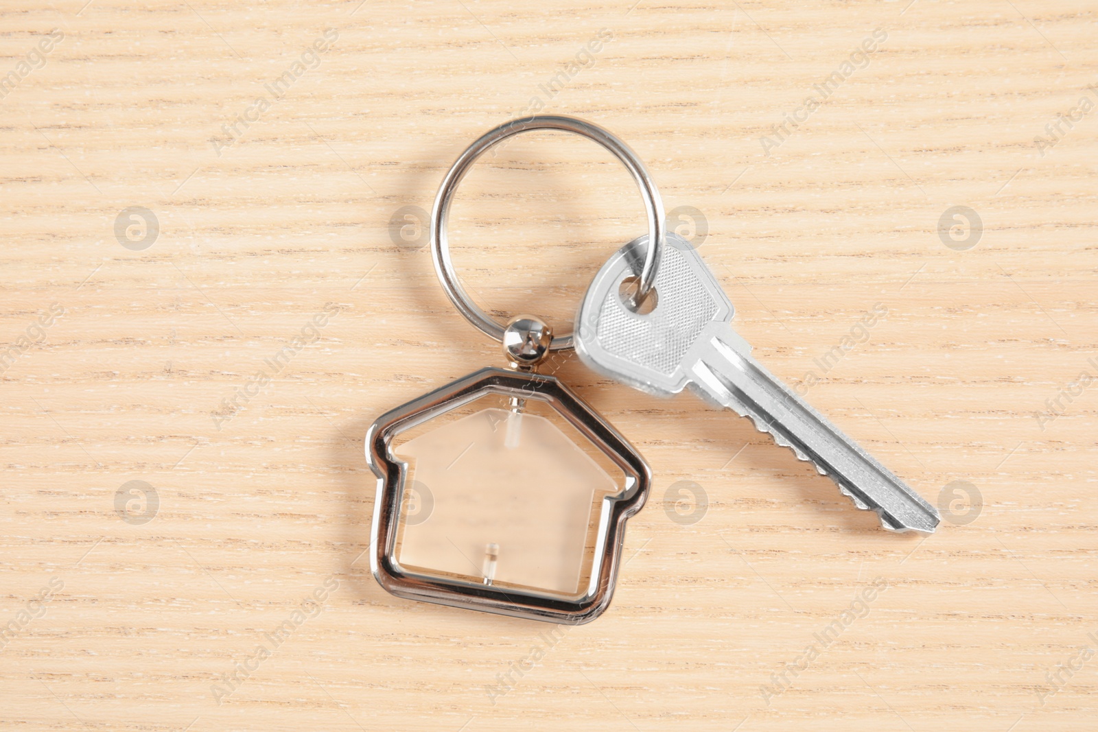 Photo of House key with trinket on wooden background, top view