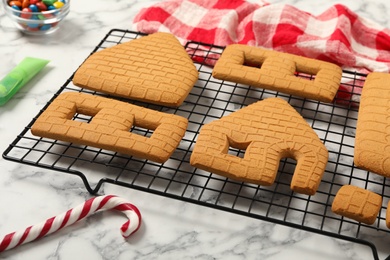 Parts of gingerbread house and candy cane on white marble table