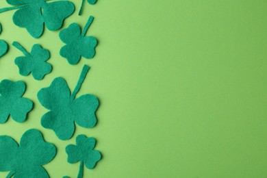 Photo of St. Patrick's day. Decorative clover leaves on green background, flat lay. Space for text