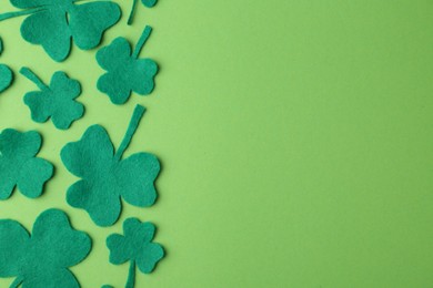 St. Patrick's day. Decorative clover leaves on green background, flat lay. Space for text