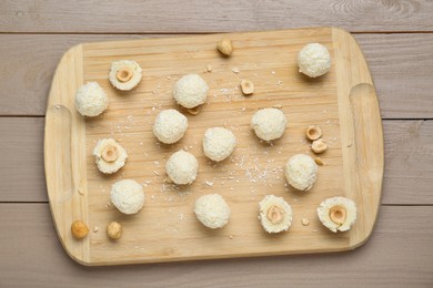 Photo of Delicious candies with coconut flakes and hazelnut on wooden table, top view
