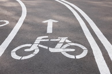 Photo of Bicycle lane with sign and arrow pointing direction on asphalt