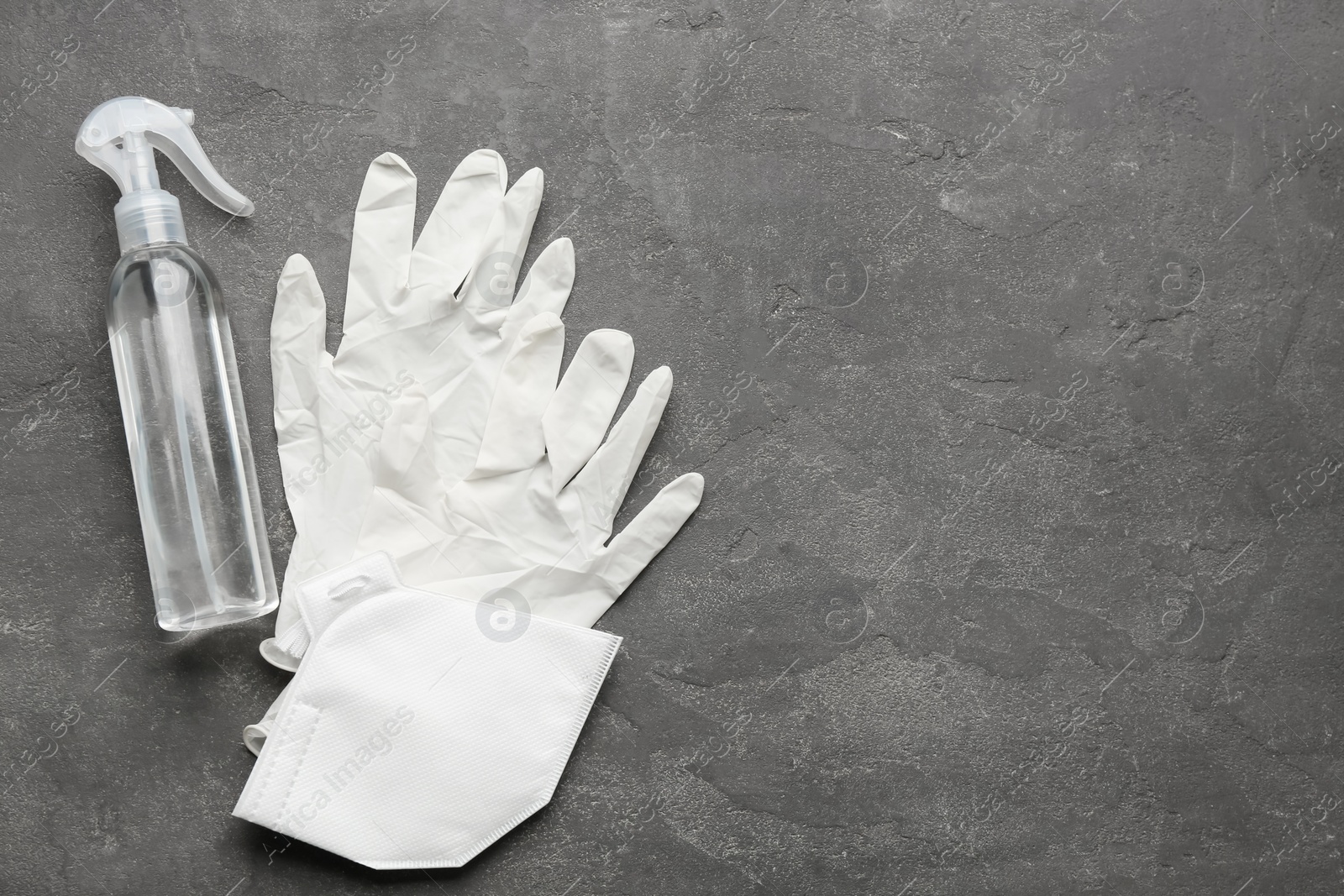 Photo of Medical gloves, protective mask and hand sanitizer on grey background, flat lay. Space for text