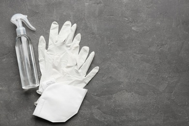 Medical gloves, protective mask and hand sanitizer on grey background, flat lay. Space for text