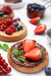 Photo of Tasty organic rusks with different toppings and ingredients on white table, closeup