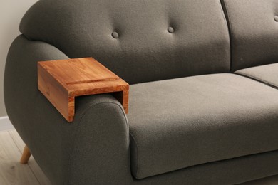 Photo of Wooden armrest table on sofa in room. Interior element