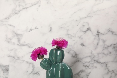 Photo of Trendy cactus shaped ceramic vase with flowers on marble background