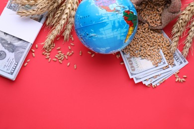 Photo of Import and export concept. Globe, ears of wheat and money on red background, flat lay with space for text