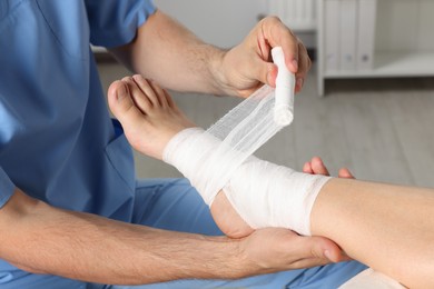 Photo of Doctor applying bandage onto patient's foot in hospital, closeup