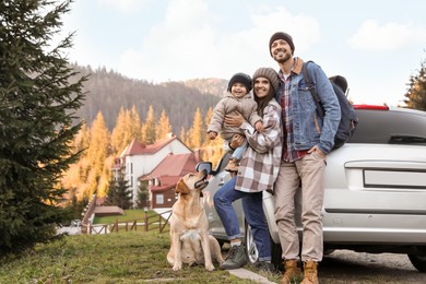 Parents, their daughter and dog near car in mountains, space for text. Family traveling with pet
