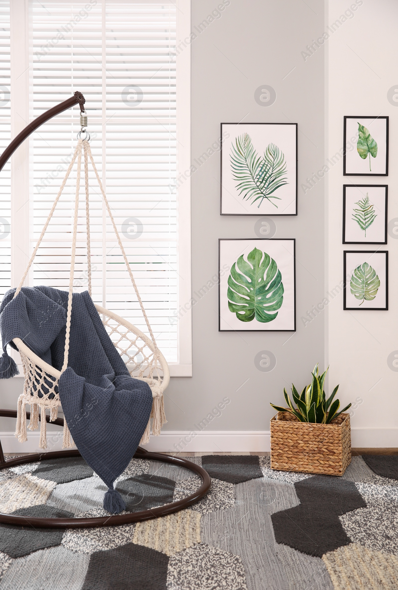 Photo of Stylish room interior with artworks and hanging chair